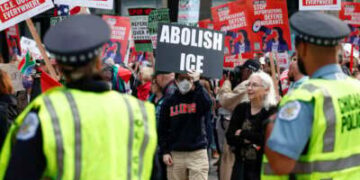 Los oficiales de policía observan mientras las personas participan en una manifestación contra el despliegue planificado de tropas de la Guardia Nacional en Chicago