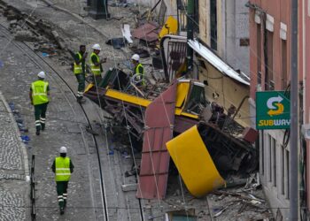 Escombros de un funicular descarrilado en Lisboa, Portugal, con trabajadores en el sitio.