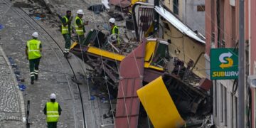 Escombros de un funicular descarrilado en Lisboa, Portugal, con trabajadores en el sitio.