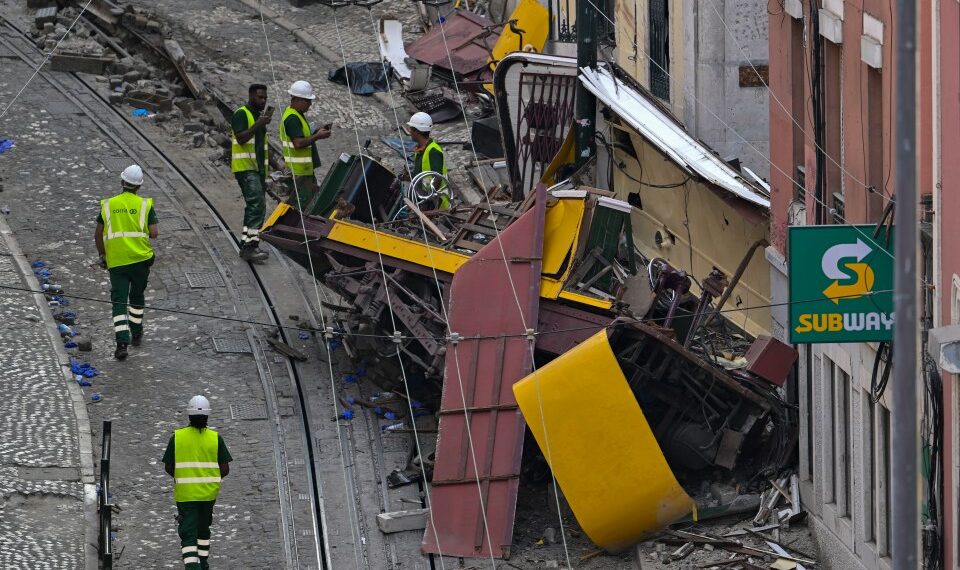 Escombros de un funicular descarrilado en Lisboa, Portugal, con trabajadores en el sitio.