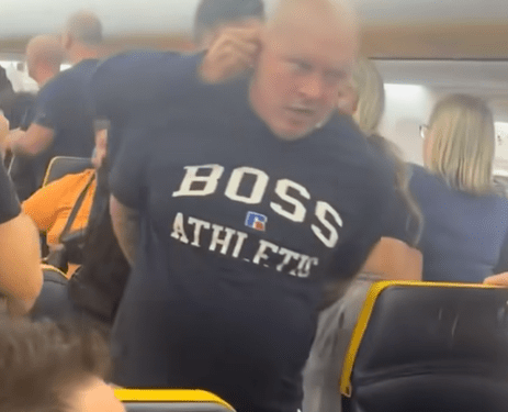 Un hombre con un "Atlético de jefe" Camisa que está restringida en un avión.