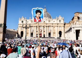Persona que sostiene un retrato de Carlo Acutis en una masa de canonización en la Plaza de San Pedro.