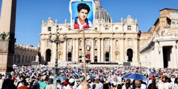 Persona que sostiene un retrato de Carlo Acutis en una masa de canonización en la Plaza de San Pedro.
