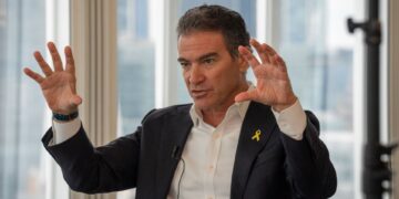 Yossi Cohen, ex jefe de Mossad, con un traje con una cinta amarilla, gestica con ambas manos durante una entrevista.