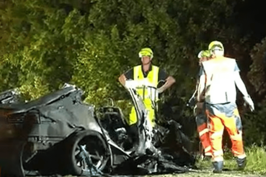 El personal de emergencia atiende a un vehículo Tesla severamente dañado y quemado después de un accidente fatal.