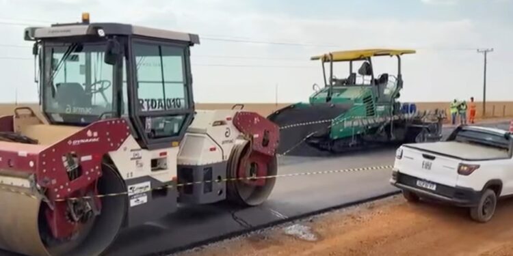 Escena de construcción de carreteras con un vapor y una máquina de pavimento.