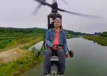 El influencer de aviación Tang Feiji volando un avión ultraligero sobre un cuerpo de agua.