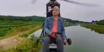 El influencer de aviación Tang Feiji volando un avión ultraligero sobre un cuerpo de agua.