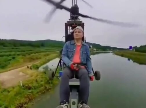 El influencer de aviación Tang Feiji volando un avión ultraligero sobre un cuerpo de agua.