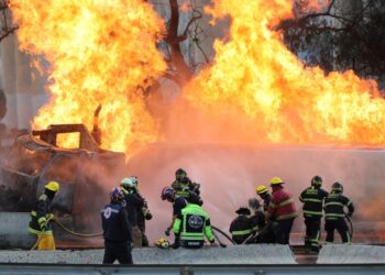 Los bomberos que luchan contra un gran incendio de gasolina de gas.