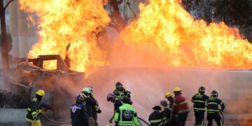 Los bomberos que luchan contra un gran incendio de gasolina de gas.