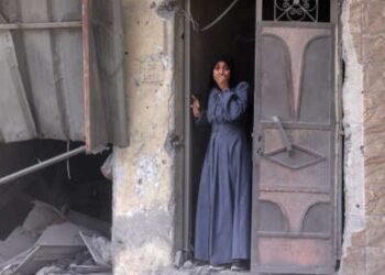 Una mujer palestina de pie en una puerta observa las secuelas de una huelga israelí que golpeó el vecindario del sur de Al-Zaytoun de la ciudad de Gaza el 8 de agosto de 2025.