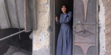 Una mujer palestina de pie en una puerta observa las secuelas de una huelga israelí que golpeó el vecindario del sur de Al-Zaytoun de la ciudad de Gaza el 8 de agosto de 2025.