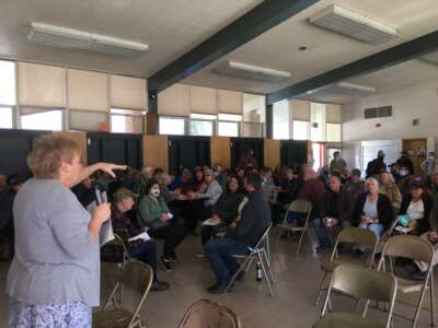 Después del incendio de Dixie de 2021, el colectivo de Indian Valley se reúne para su reunión mensual en la cafetería de la Escuela Primaria Greenville, uno de los pocos edificios en Greenville, California, para sobrevivir. Estas reuniones son donde los miembros de la comunidad comparten información vital sobre los esfuerzos de recuperación y los nuevos proyectos. Sue Weber (quien escribió una pieza en advertencia de la bandera roja) está hablando.