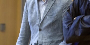 Un hombre con un blazer azul claro se encuentra en una sala del tribunal.