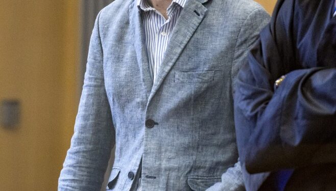 Un hombre con un blazer azul claro se encuentra en una sala del tribunal.