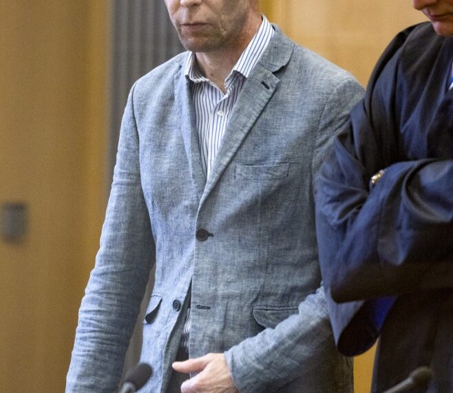 Un hombre con un blazer azul claro se encuentra en una sala del tribunal.