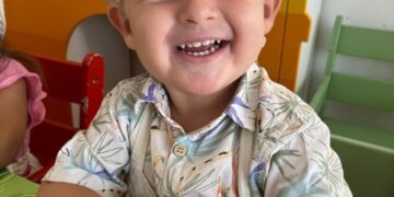 Extrañando el niño británico Oliver Pugh con un sombrero de chef y una camisa estampada, sonriendo.