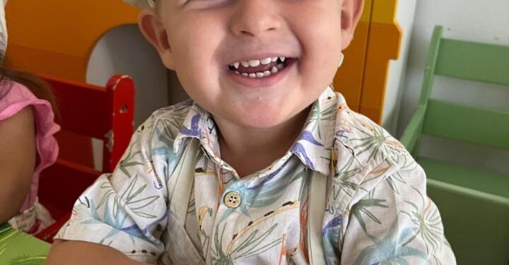 Extrañando el niño británico Oliver Pugh con un sombrero de chef y una camisa estampada, sonriendo.