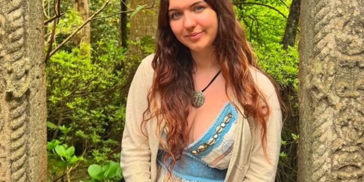 Rebecca McCurry, de 22 años, posando al aire libre con un vestido con un cárdigan blanco.