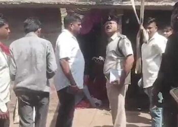 Oficial de policía que habla con personas fuera de una casa.