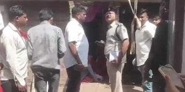 Oficial de policía que habla con personas fuera de una casa.