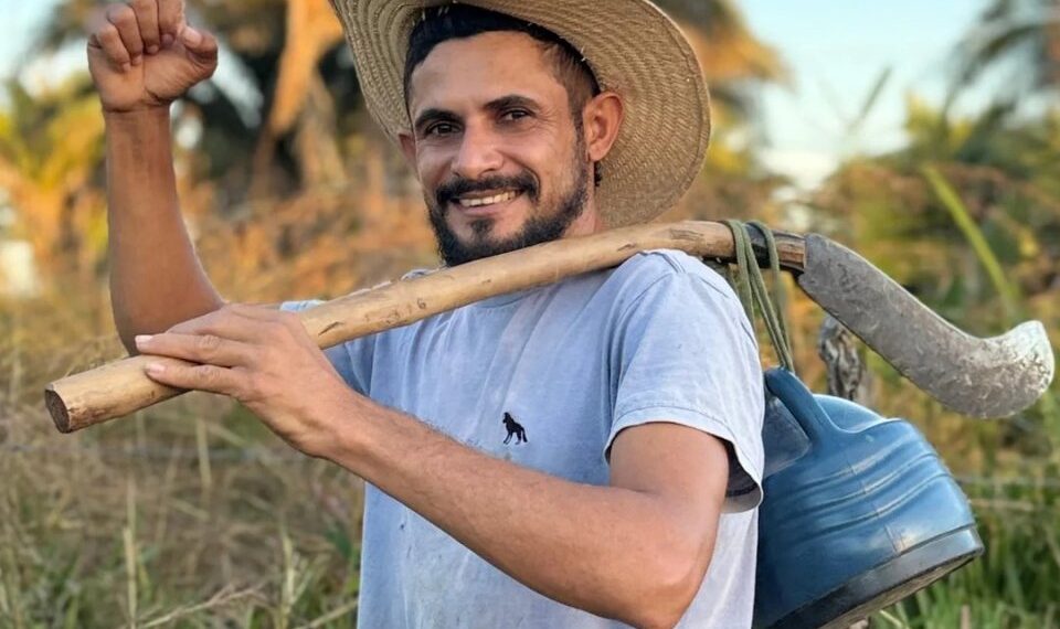 Reinaldo da Silva Melo, también conocido como el "Rey de Juquira" Influencer, llevando una guadaña sobre su hombro.