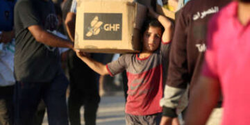 Un niño que lleva una parcela de ayuda, camina por la carretera Salah al-Din, cerca del campo de refugiados de Nusseirat en la franja central de Gaza, utilizado por los palestinos que buscan alimentos para alcanzar un punto de distribución de ayuda establecido por la Fundación Humanitaria de Gaza privada (GHF), el 25 de junio de 2025.