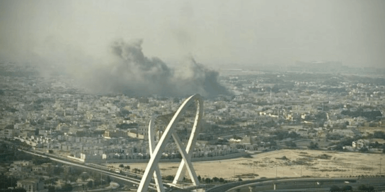 Vista aérea de una ciudad con un gran penacho de humo negro y un puente moderno.