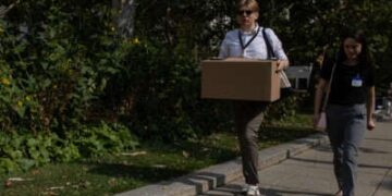 Recientemente despedidos de los empleados del Departamento de Estado de EE. UU. Llevan cajas mientras salen del Edificio Federal de Harry S. Truman el 11 de julio de 2025 en Washington, DC