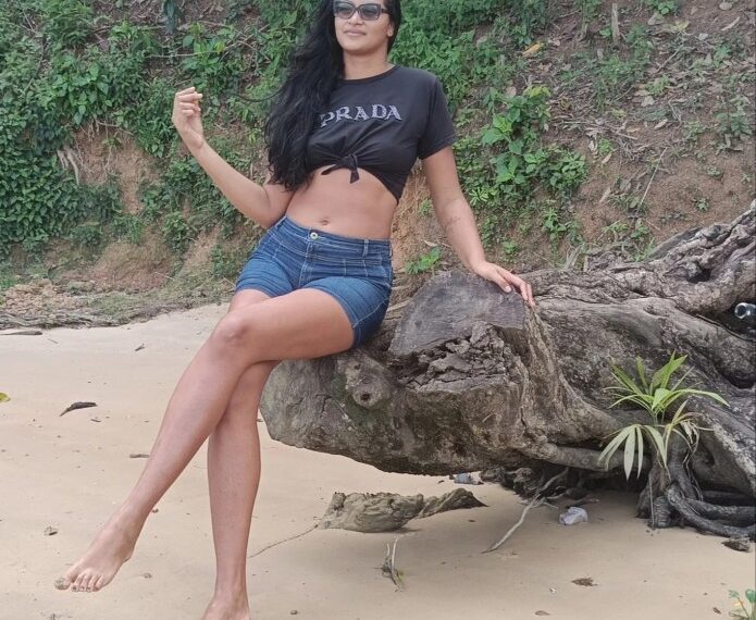 Mujer sentada en un registro en una playa de arena.