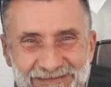 Un hombre con barba gris y gafas de sol en la cabeza sonriendo ligeramente.