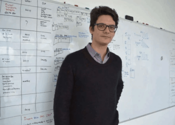 Matias Augusto Travizano se encuentra frente a una pizarra llena de notas y diagramas.