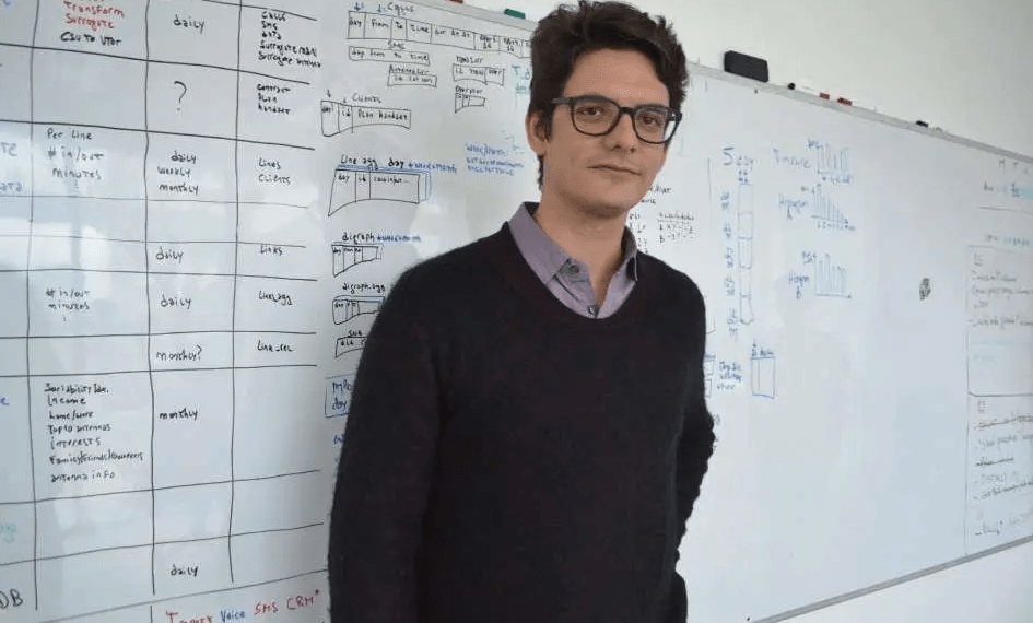 Matias Augusto Travizano se encuentra frente a una pizarra llena de notas y diagramas.