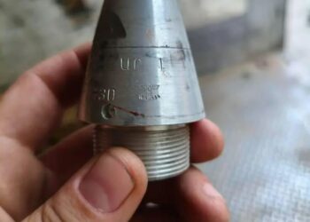 Una mano que sostiene un arma nazi con una esvástica y marcas.