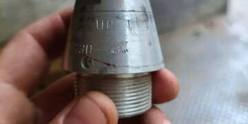 Una mano que sostiene un arma nazi con una esvástica y marcas.