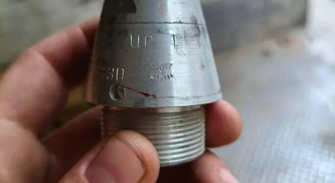 Una mano que sostiene un arma nazi con una esvástica y marcas.