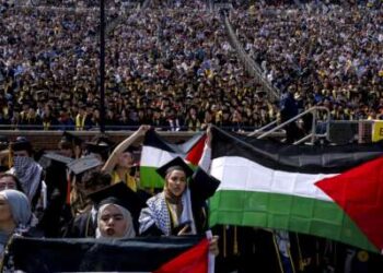 Salma Hamamy, centro, posee una bandera de Palestina durante la ceremonia de inicio de primavera de la Universidad de Michigan el 4 de mayo de 2024 en el estadio de Michigan en Ann Arbor, Michigan.