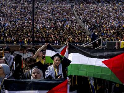 Salma Hamamy, centro, posee una bandera de Palestina durante la ceremonia de inicio de primavera de la Universidad de Michigan el 4 de mayo de 2024 en el estadio de Michigan en Ann Arbor, Michigan.