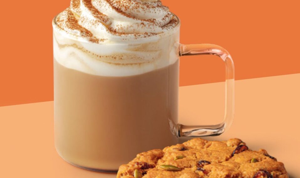 Un café con leche de especias de calabaza Starbucks con crema batida y una galleta con arándanos y semillas de calabaza.