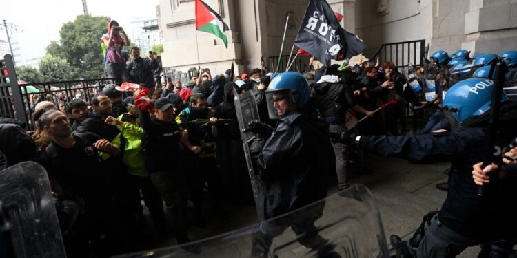 Los manifestantes chocan con la policía antidisturbios en una estación de tren.