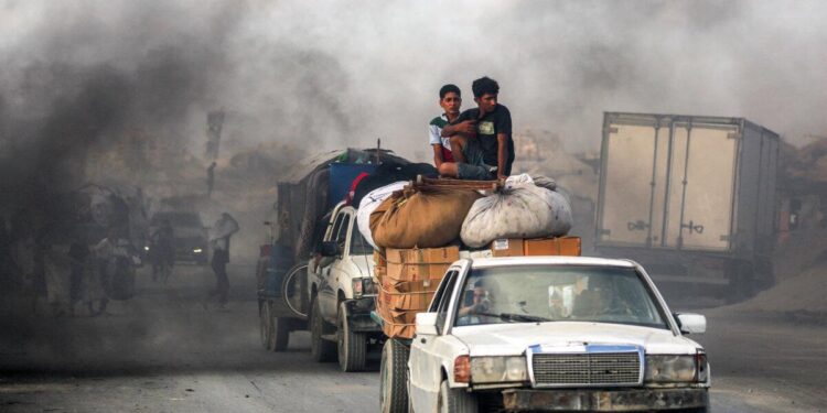 Los jóvenes montan en los paquetes y muebles en un carro remolcado por otro vehículo mientras las personas evacúan hacia el sur desde la ciudad de Gaza el 2 de septiembre de 2025. (Eyad Baba/AFP a través de Getty Images)