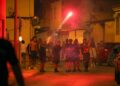 Los manifestantes se enfrentan con la policía por la noche.