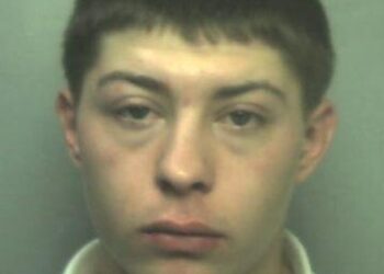 Mugshot de un joven con cabello corto y oscuro, con una camisa blanca.