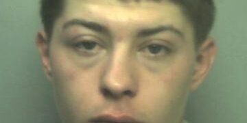 Mugshot de un joven con cabello corto y oscuro, con una camisa blanca.