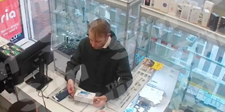 Las imágenes de CCTV muestran a un hombre con una sudadera con capucha negra que compraba un teléfono en un mostrador en una tienda.