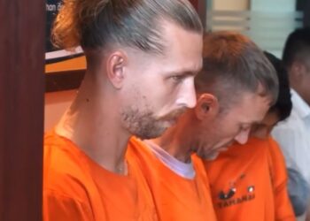 Dos hombres británicos con monos de naranja en una conferencia de prensa después de su arresto por presuntamente contrabando de cocaína.