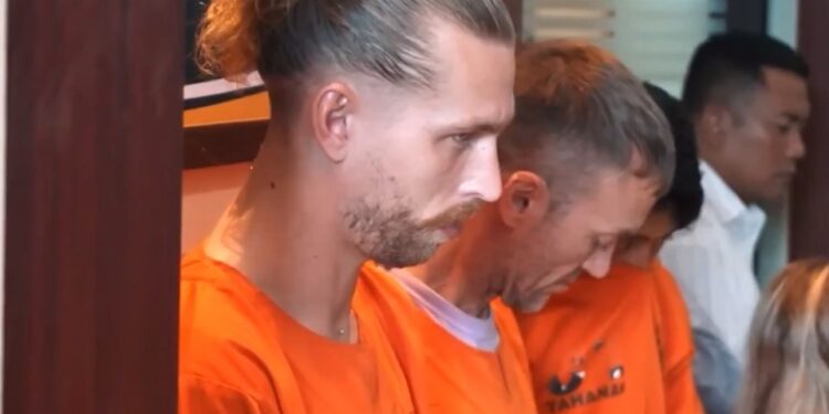 Dos hombres británicos con monos de naranja en una conferencia de prensa después de su arresto por presuntamente contrabando de cocaína.