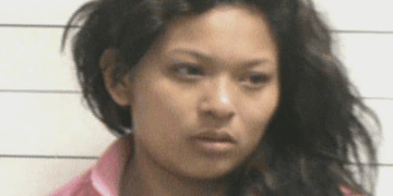 Una mujer con cabello oscuro y ondulado y una chaqueta rosa.