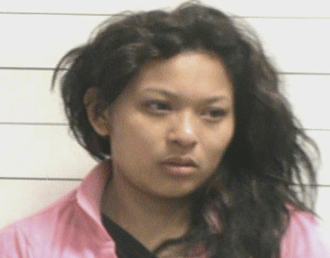 Una mujer con cabello oscuro y ondulado y una chaqueta rosa.